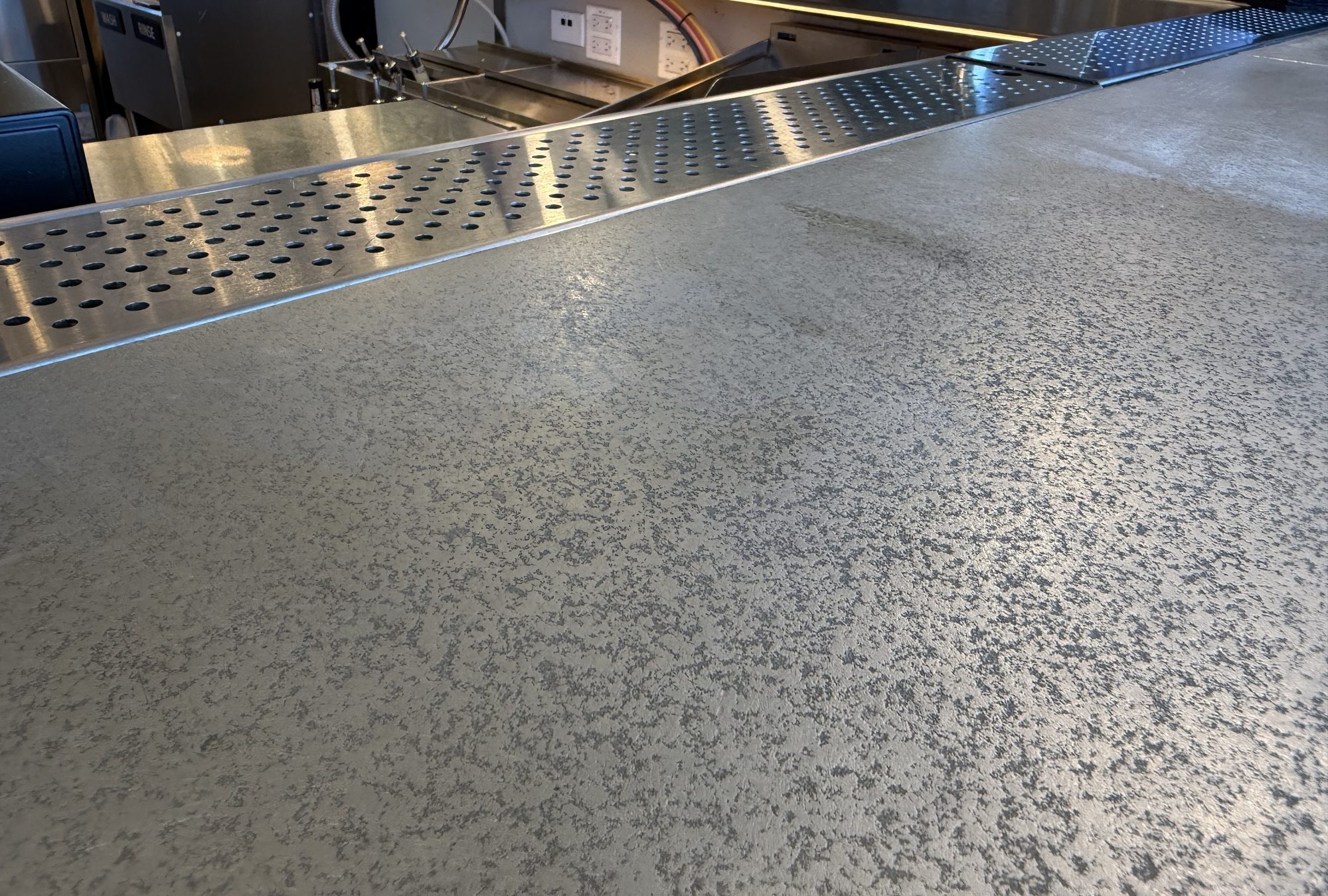 Zinc bar surface meeting the KegWorks stainless drink rail at The Bar by Black Tap, JFK Terminal 8, New York