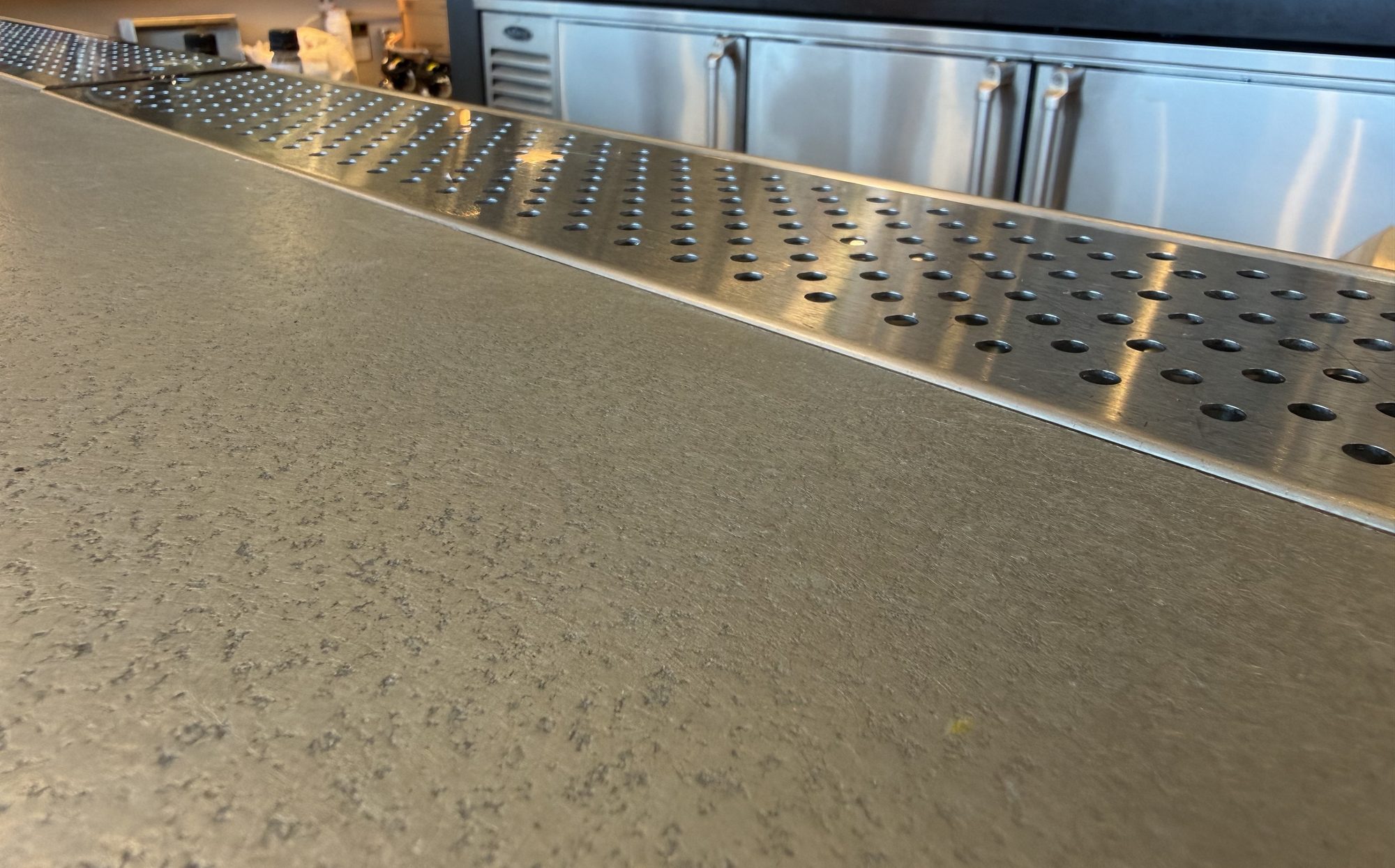 Zinc bar surface catching the light in front of the back bar at Black Tap, JFK Terminal 8, New York