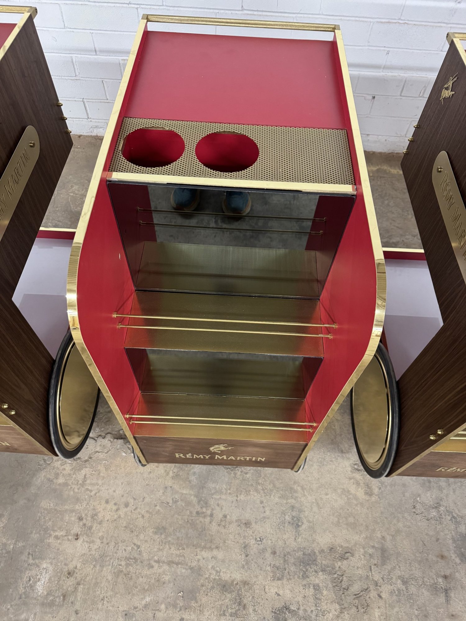 Front of a Rémy Martin bar cart with brass shelf rails and mirrored back