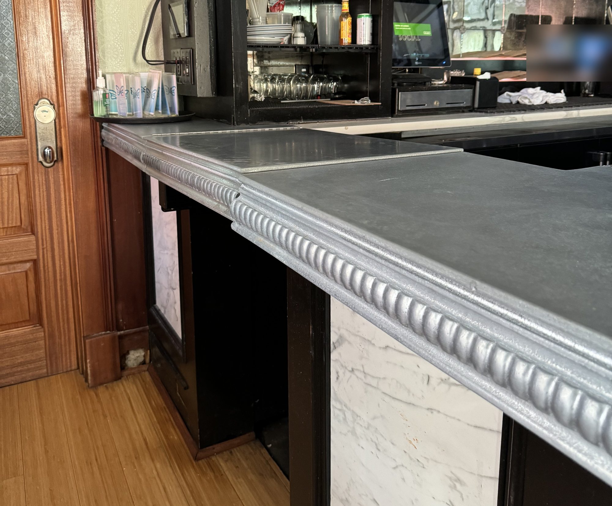 Flip gate closed at the service end of the zinc bar, with the pillowed edge carried across, Uptown Social, Charleston